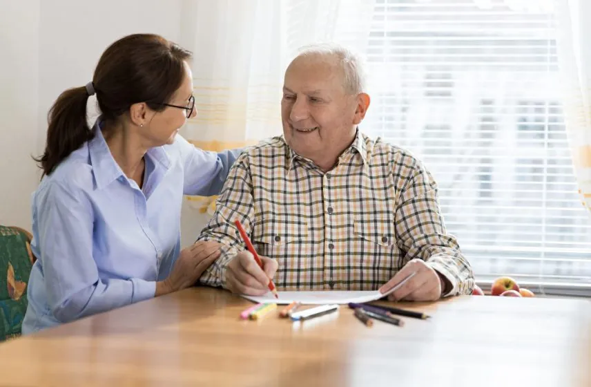 Therapist working one-on-one with an older adult at his kitchen table