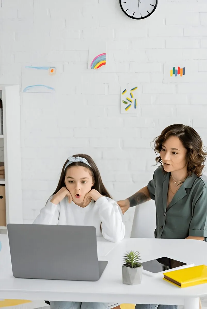 Child working with a speech therapist over a laptop during a telehealth session